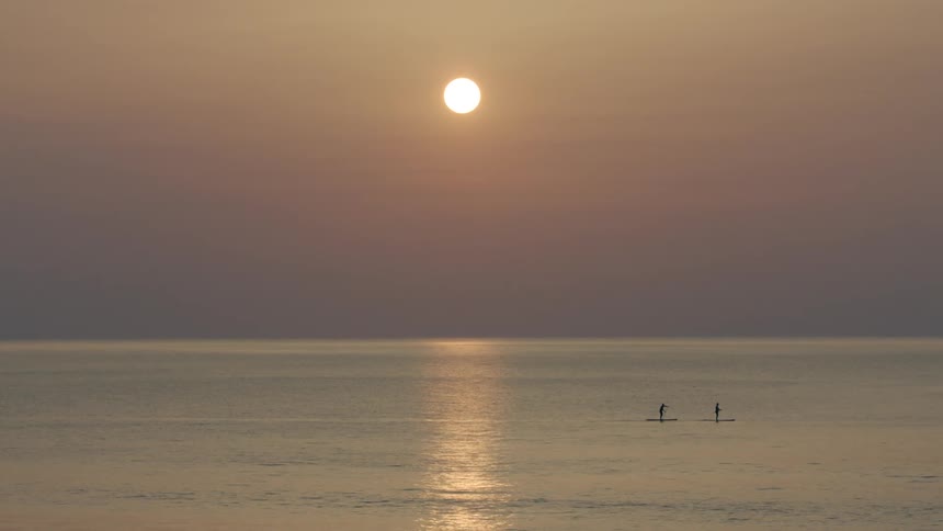 Two surfers paddle on their surfboards in the ocean