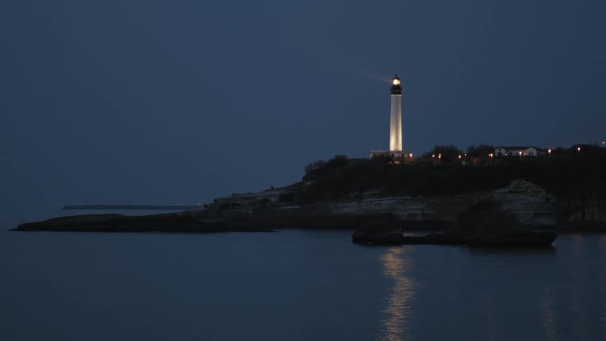 A light house is shining light on the ocean water