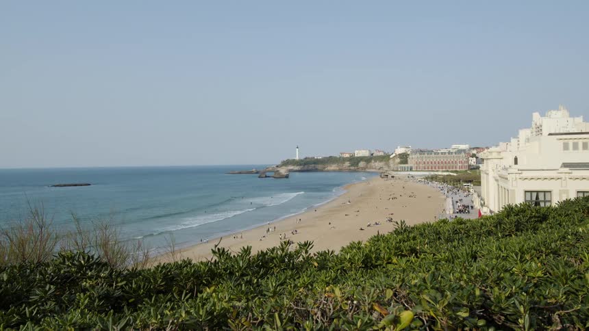 Beachgoers on the beach in front of a hotel next to the ocean