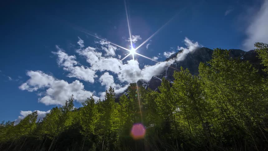 Clouds float over a mountain and trees