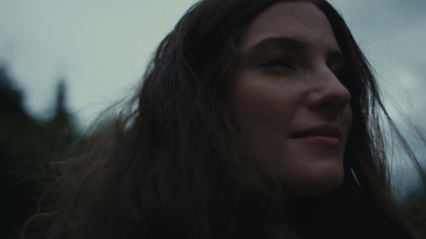 A woman looks around at her surroundings while standing outdoors in the evening