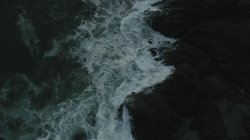 Ocean waves wash into a stone coastline