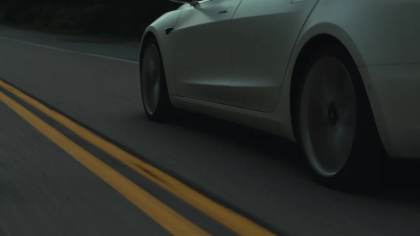 White sports car driving on a road through the countryside at evening