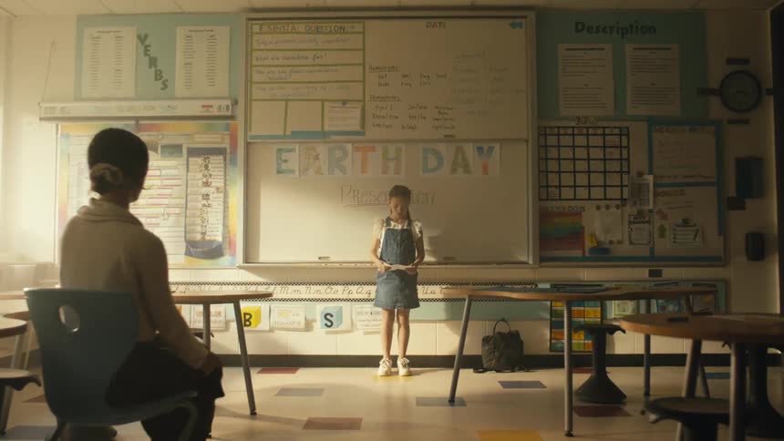 Teacher sits down while a student reading homework in the classroom