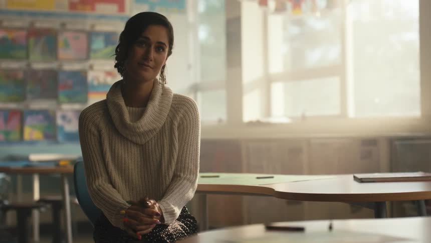 Teacher sitting on a classroom at morning listens to a student