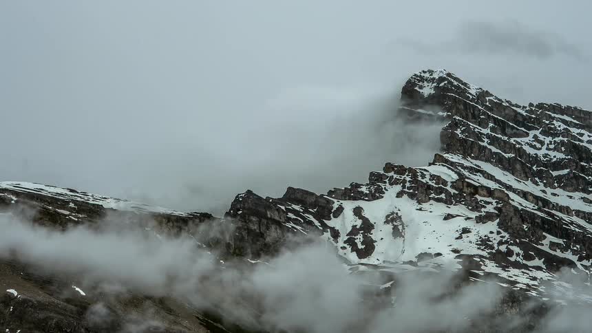 Clouds float over a snowy mountain ridge