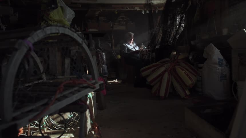 A man is sitting in a shop working on something