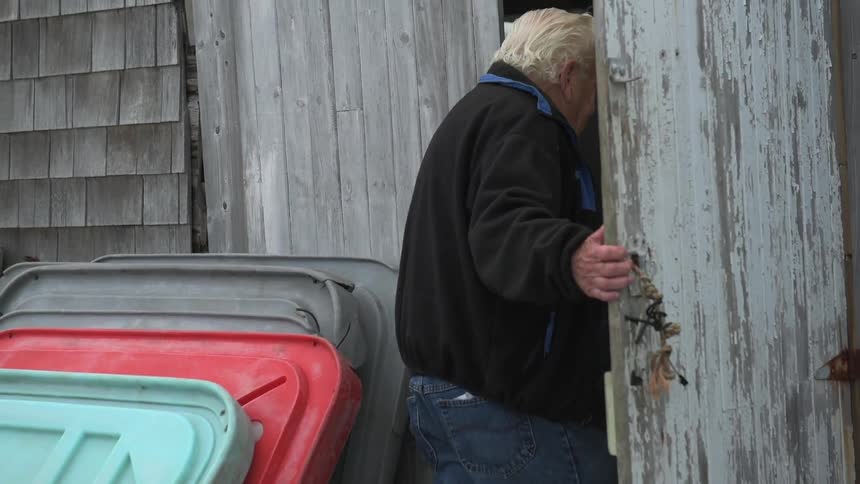 Man opens a dilapidated shed door