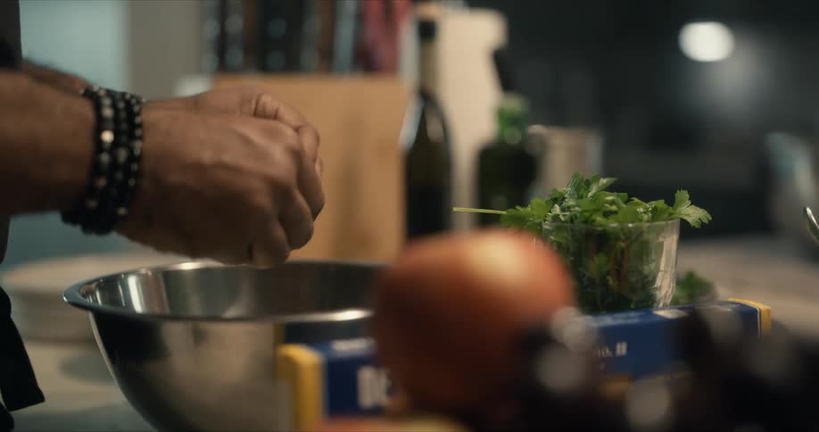 A man tears up herbs while cooking at home
