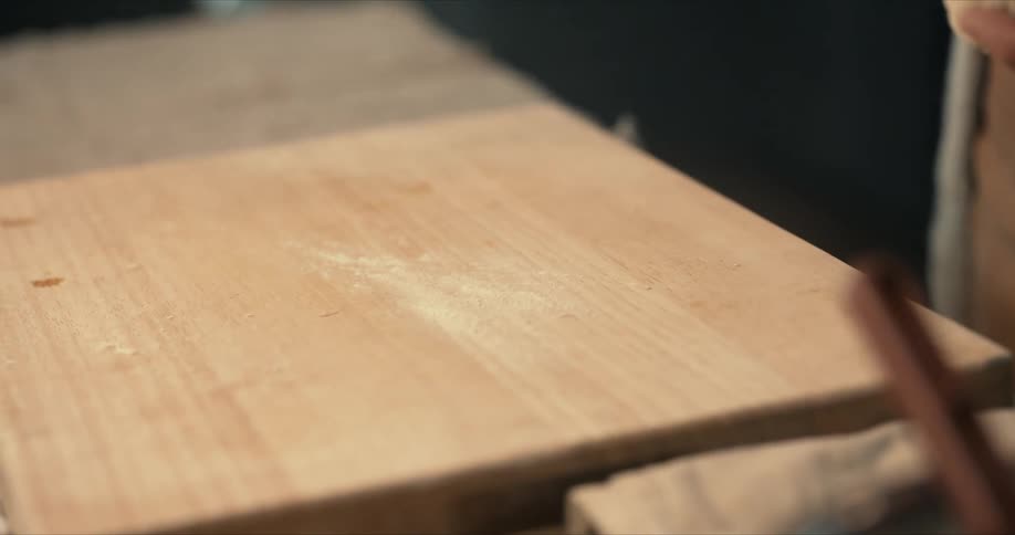 A man sprinkles flour onto a cutting board before kneading dough atop the board