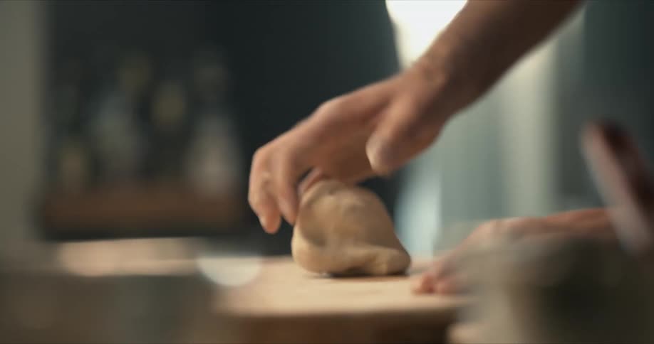 A man kneads a ball of dough on the counter