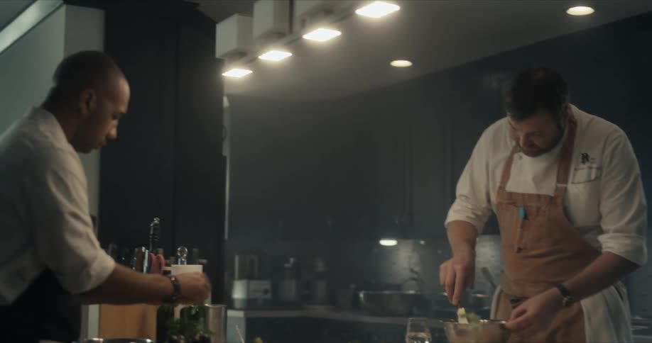 A pair of chefs cook together in a kitchen during the day