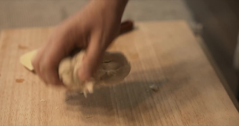 A man takes a ball of dough from a bowl and begins to knead it on a wooden cutting board