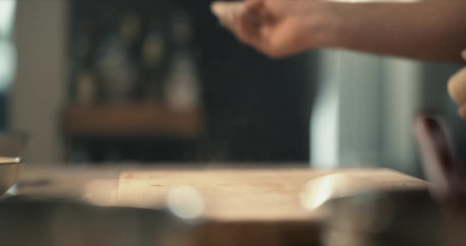 A man throws flour on a cutting board for kneading dough