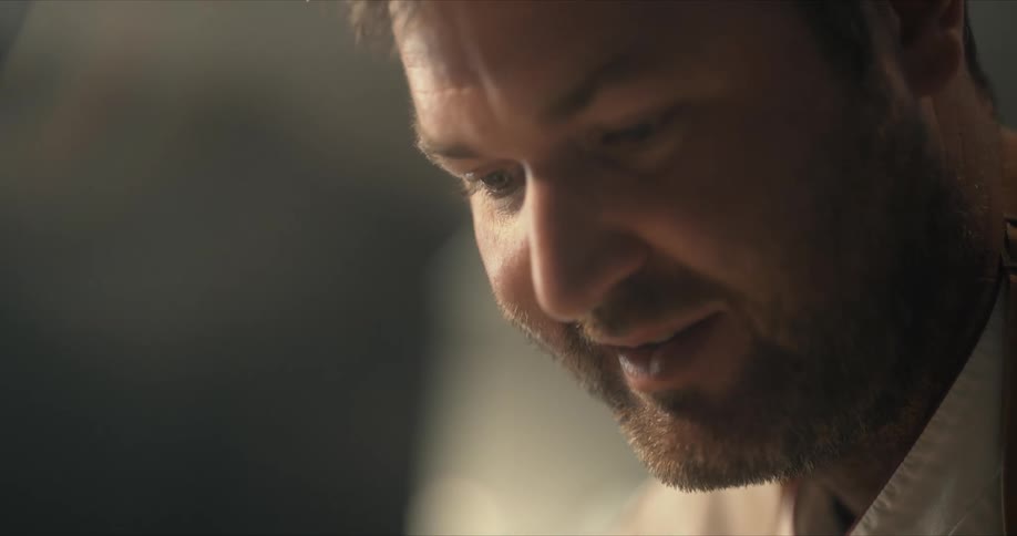 A man smiles and laughs while looking down