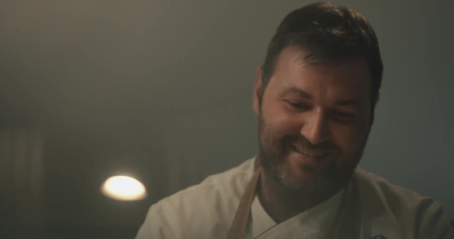 Light is shining on a man's face as he smiles and talks