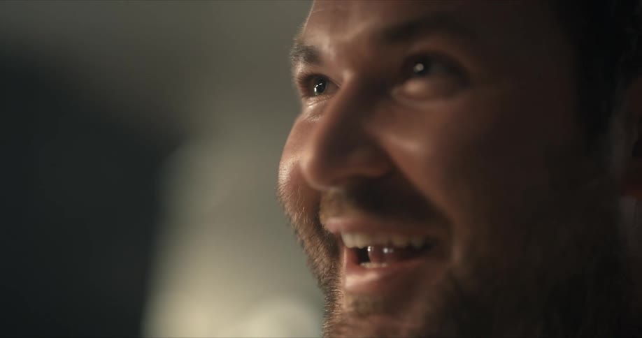 Light is shining on a man's face as he smiles and talks