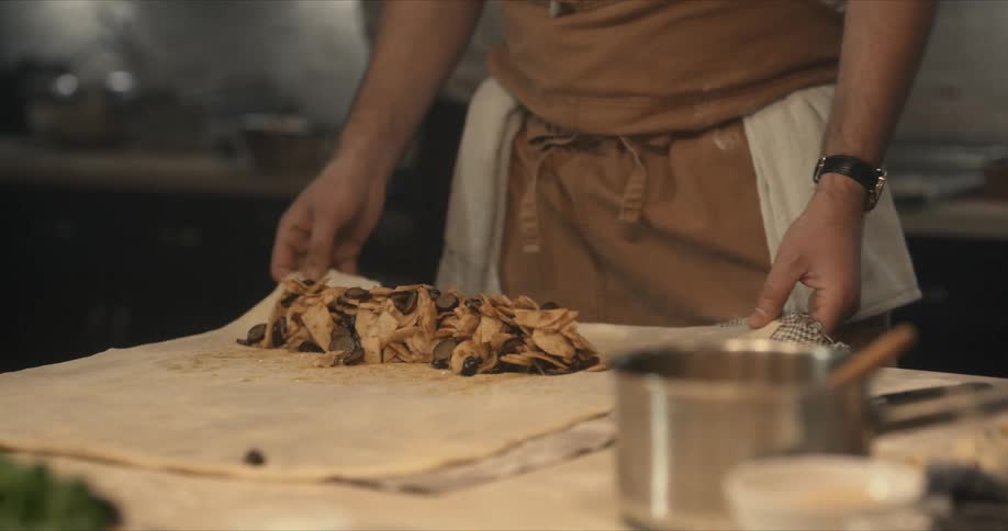 A chef is in a kitchen rolling an apple strudel