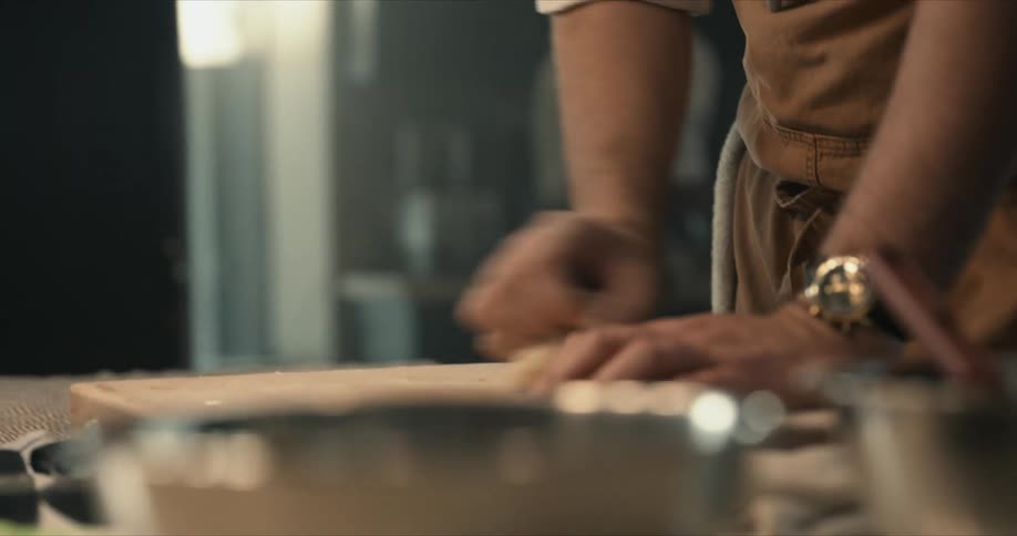 A chef is rolling dough on the cutting board