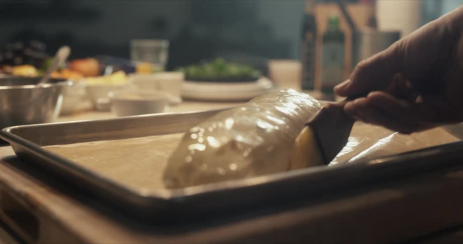 Close up of a hand coating butter on bread ready to be baked