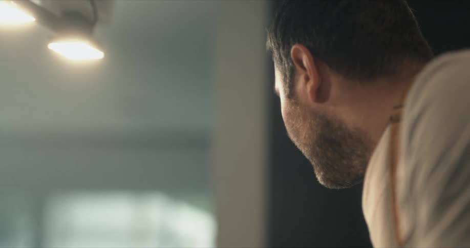 Light is shining on a man's face as he is looking down at something