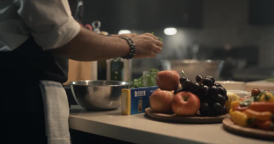 A male chef breaks apart herbs in a large kitchen