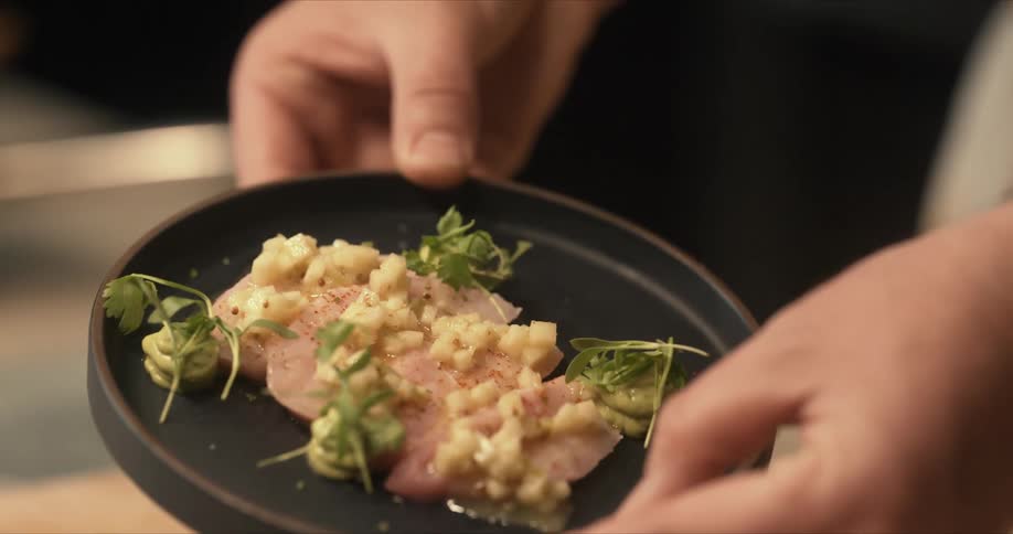 A person picks up a prepared dish and shows it off
