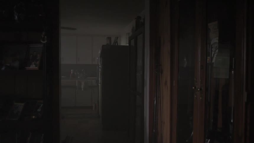 A man opens the refrigerator inside a dark house