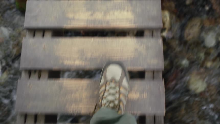 A person crosses the small wooden bridge