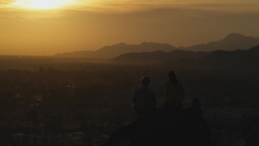 Two people sit watching the sunset