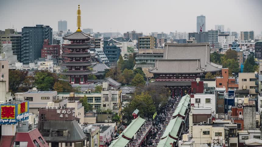 Crowd of people walk on the walkway near the city buildings in the orient