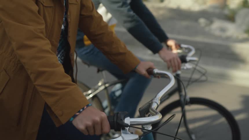Two teenagers are riding bicycles in the street on a sunny day