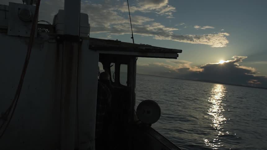 A boat is floating in the water at sunset