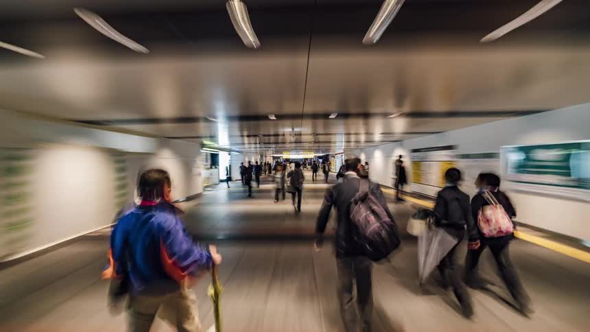 Pedestrians walk down a long corridor inside a building
