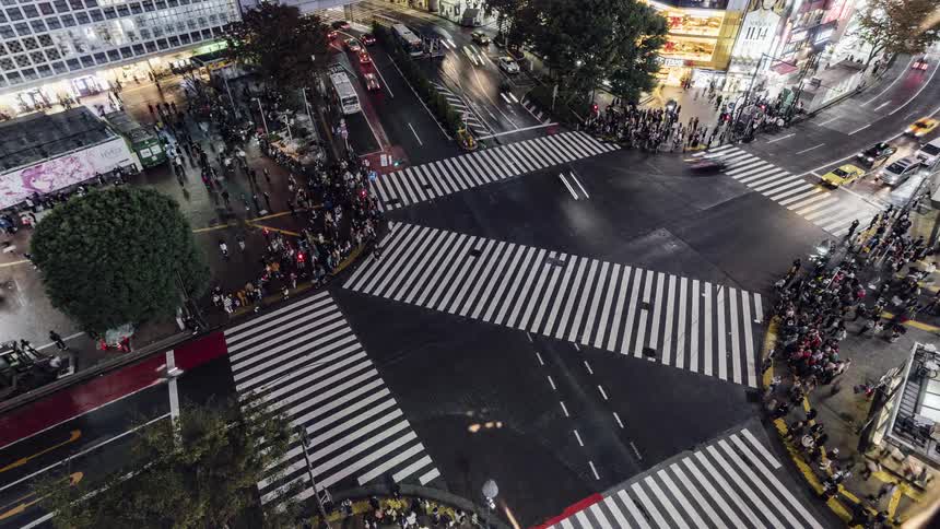 Pedestrians and traffic cross a busy intersection in a metropolis