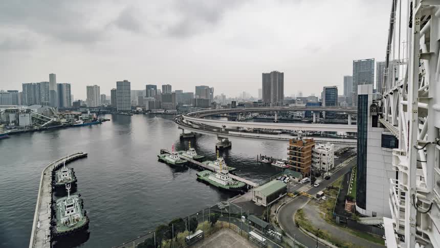 Traffic travels along a multilevel freeway over a water in a metropolis on a cloudy day