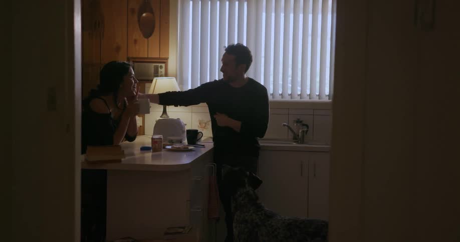A man and woman are talking and having breakfast at a kitchen counter
