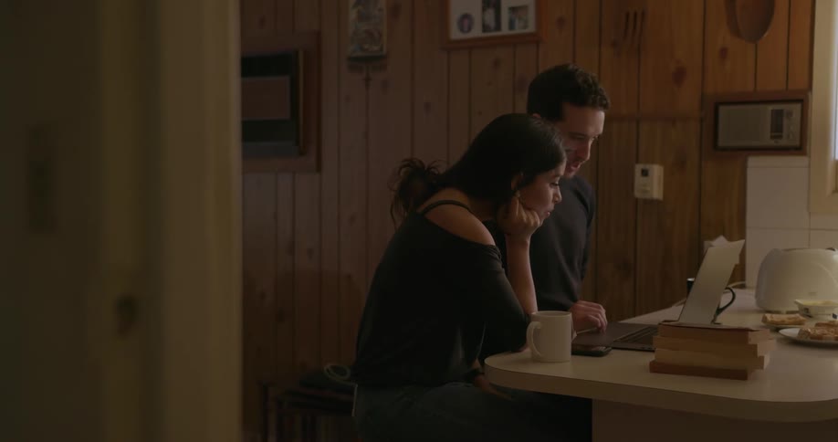 A couple work at a laptop in a kitchen