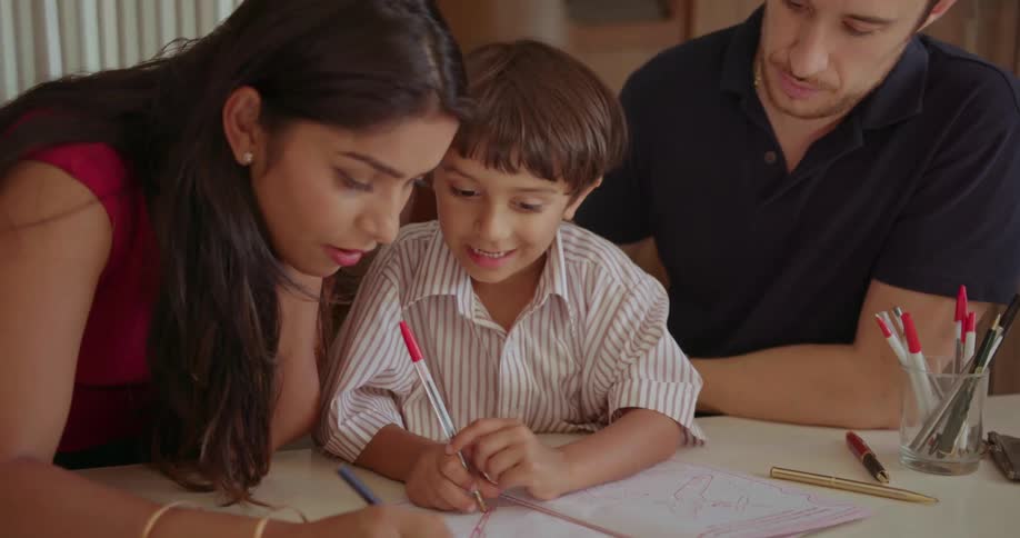Man and woman sit at table coloring with kids