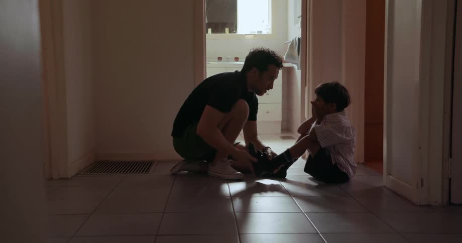 A man helps a young boy dress for school