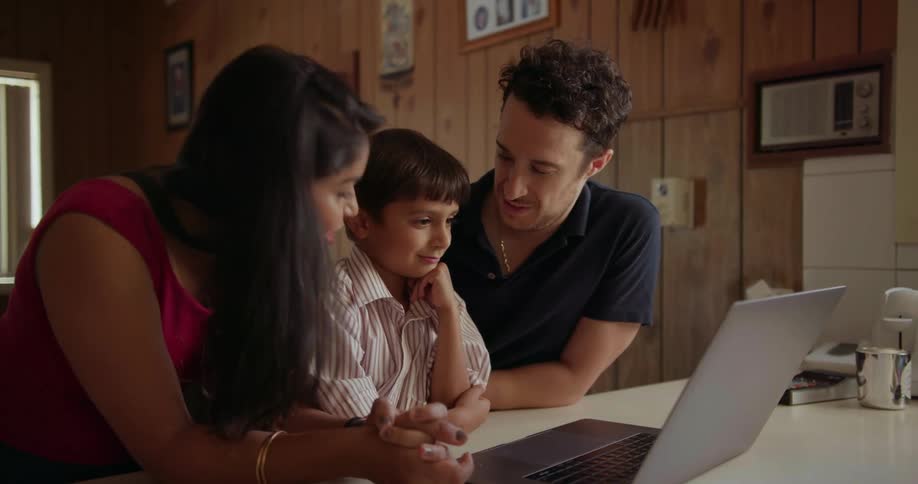 A young family is gathered around a laptop