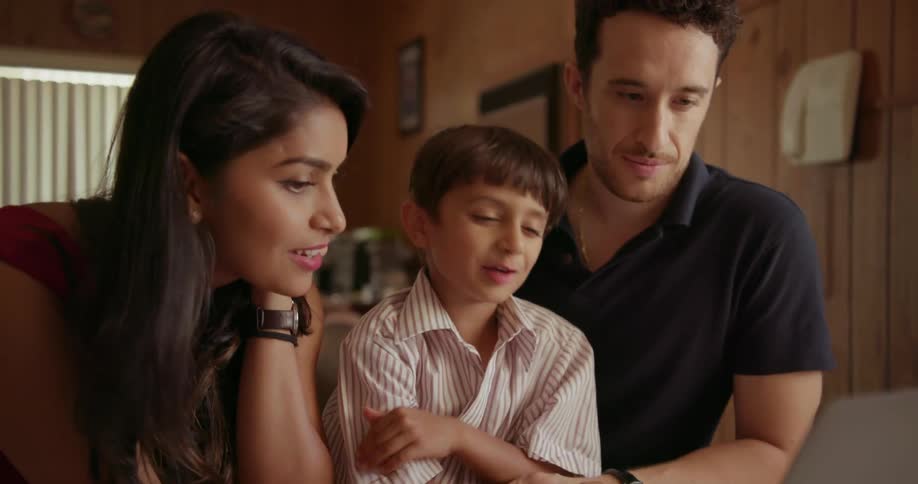 A mother, father and child use a laptop together