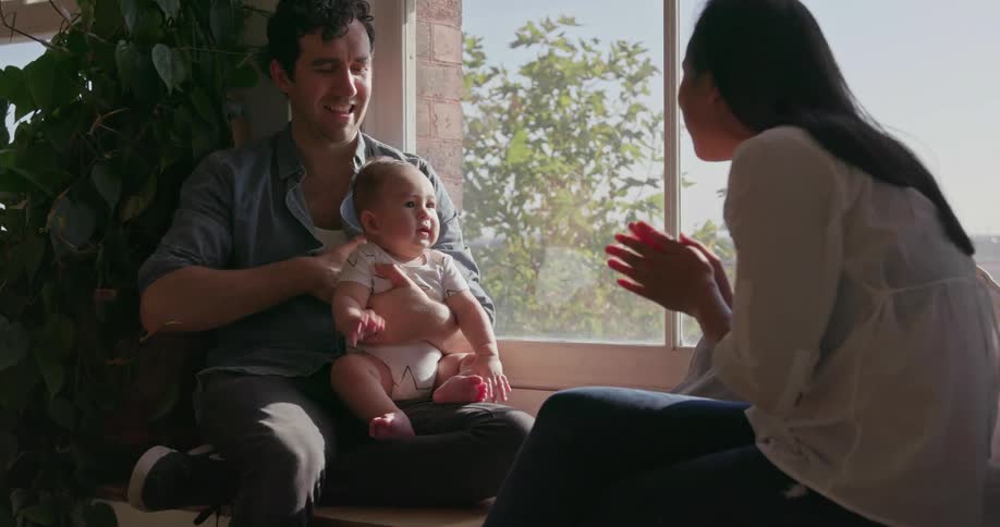 A family are playing with a baby next to a window