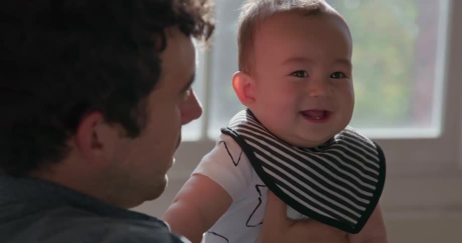 A man holds a happy baby that is laughing