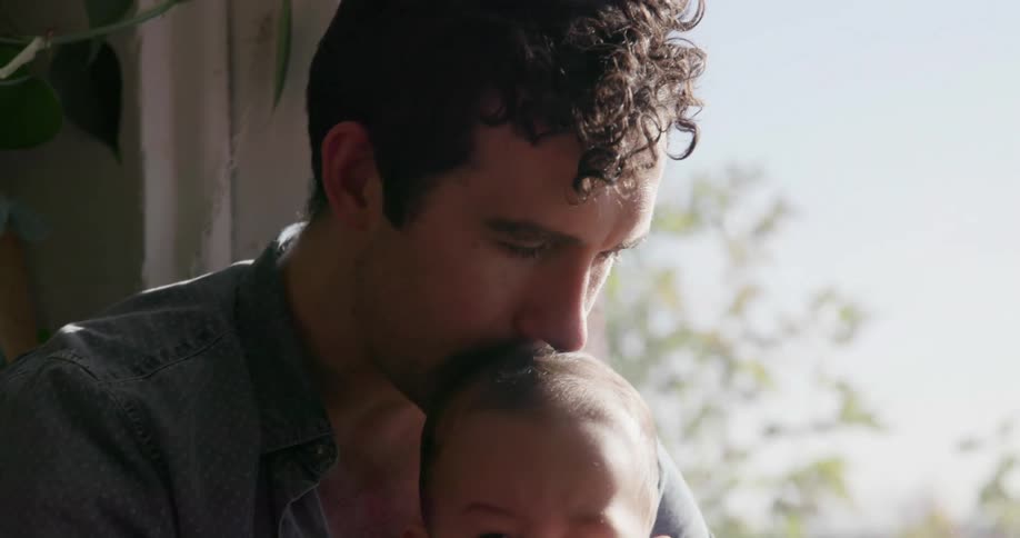 A man holds a baby near the window