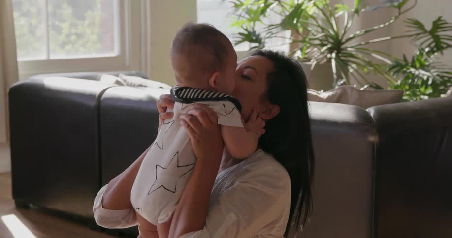 A woman lifts a baby up and gives him a hug