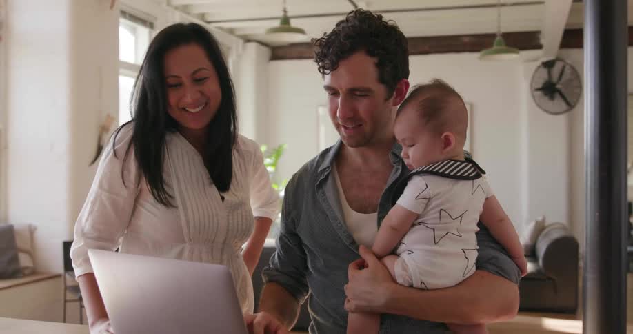 A young couple and baby look at a laptop