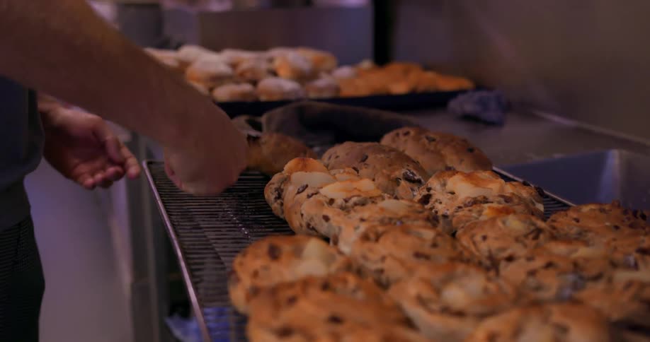 A person arranges baked goods on a tray