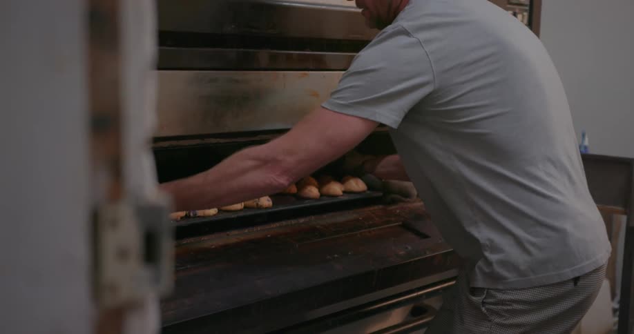 A man opens the oven to remove a tray