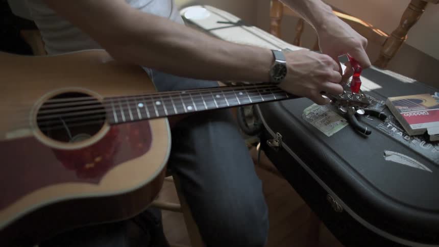 A man adjusts his guitar removing one string